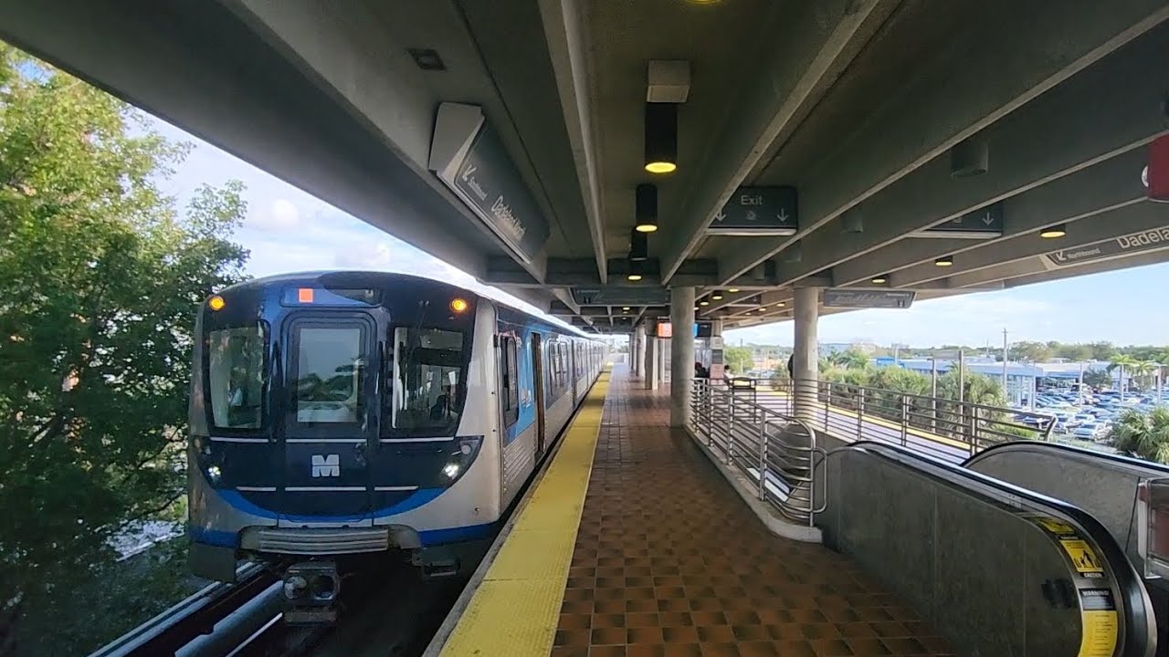 Miami Metrorail Southbound Orange Line train arriving and departing at Dadeland North Station.
