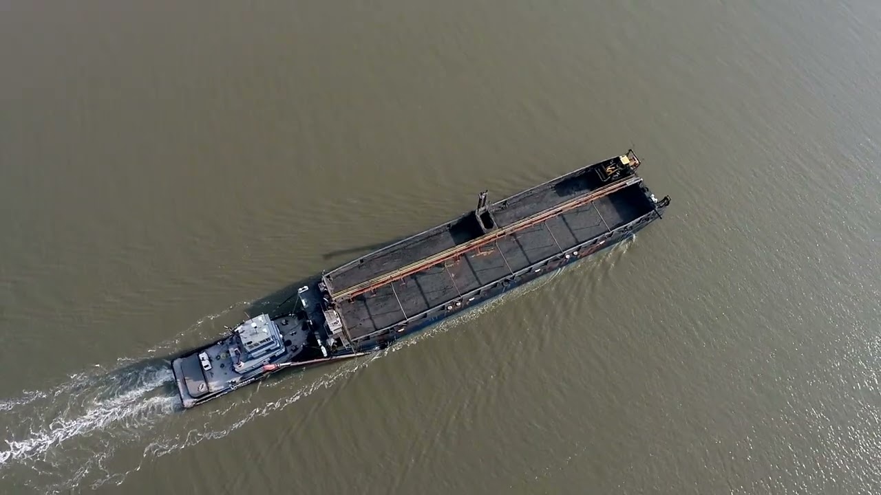 A tug and barge navigates the Petaluma River through the old railroad swing bridge