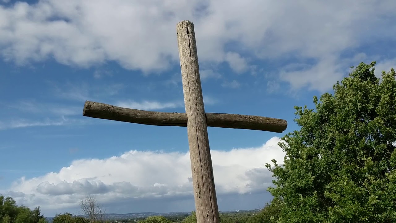 Long grass, wind and a wooden cross at Saint Arilda's church in Oldbury-on-Severn, England.