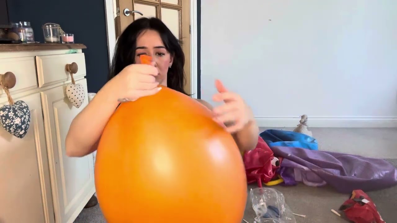 Blowing up an orange punch bag balloon