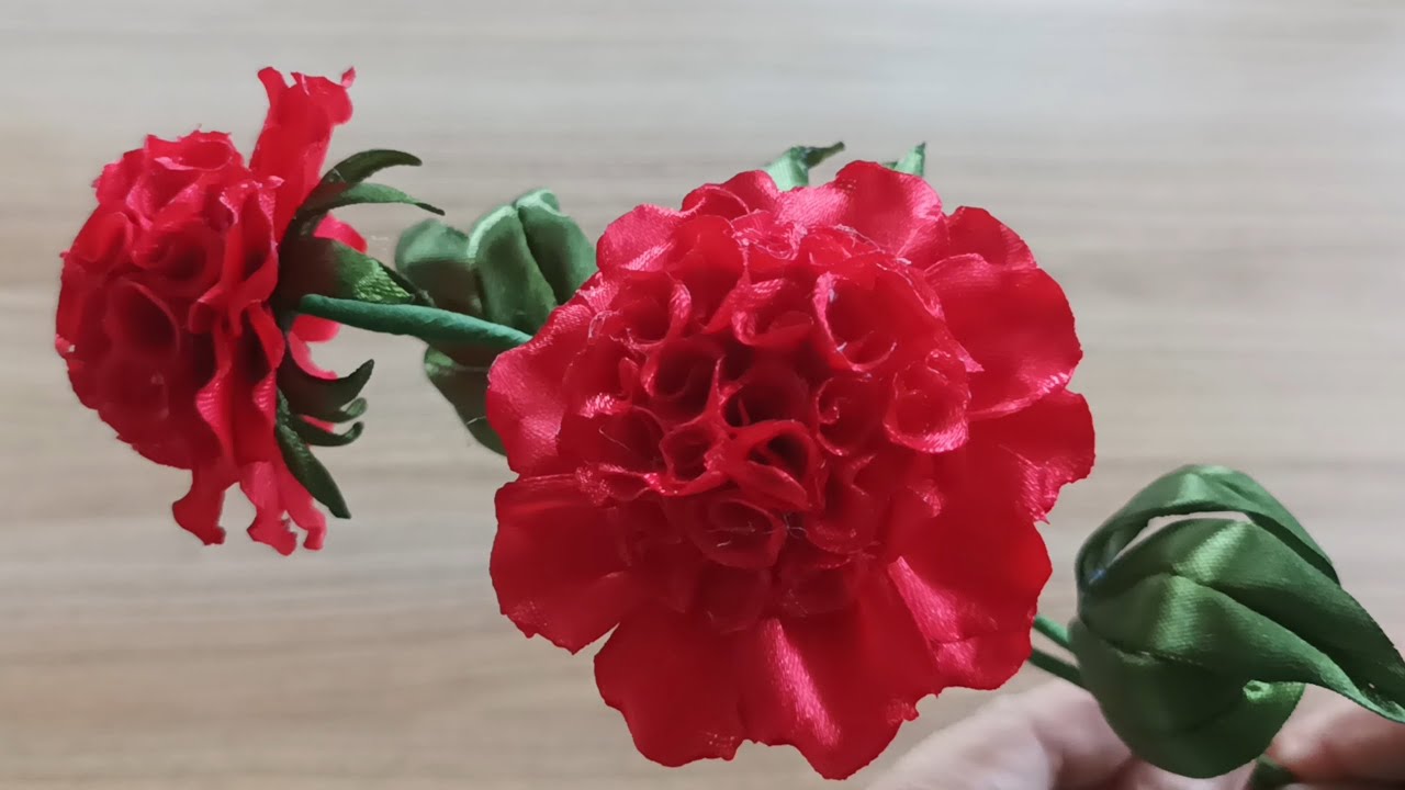 This is an artificial carnation made from red satin ribbon.