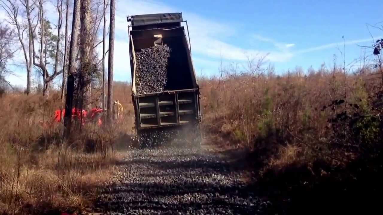 Dump truck with straight pipe spreading rock