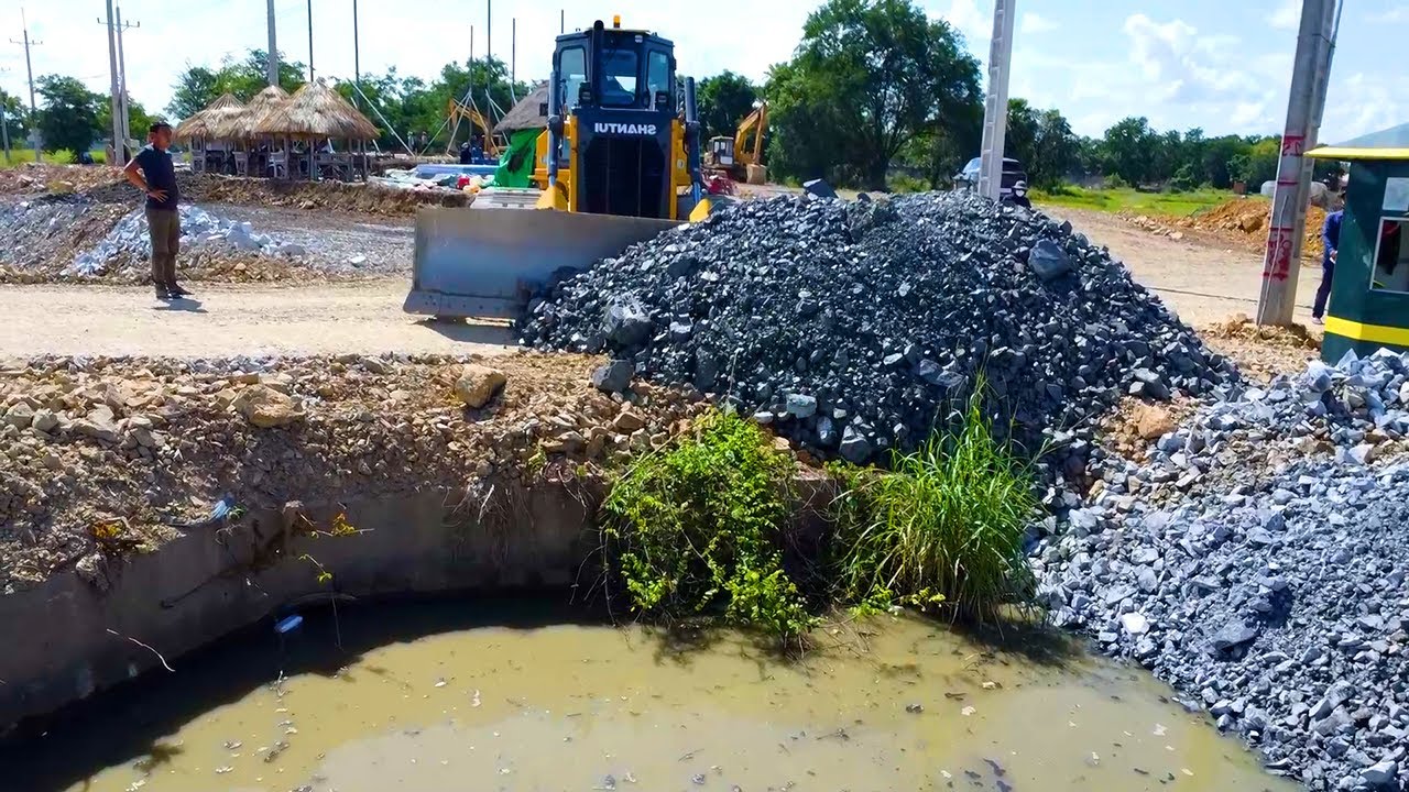 Start delete pit canal to build drainage system by SHANTUI dozer pour stone with dump truck