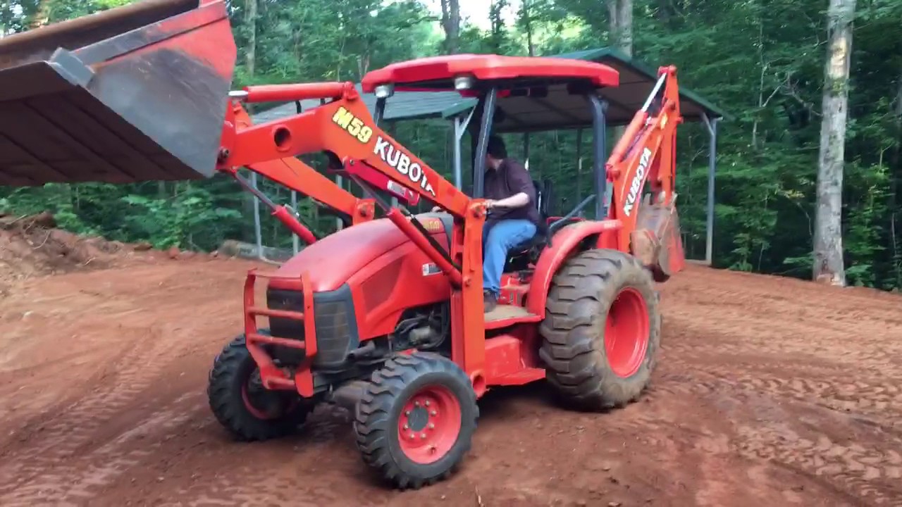 Kubota M59 backhoe moving metal carport