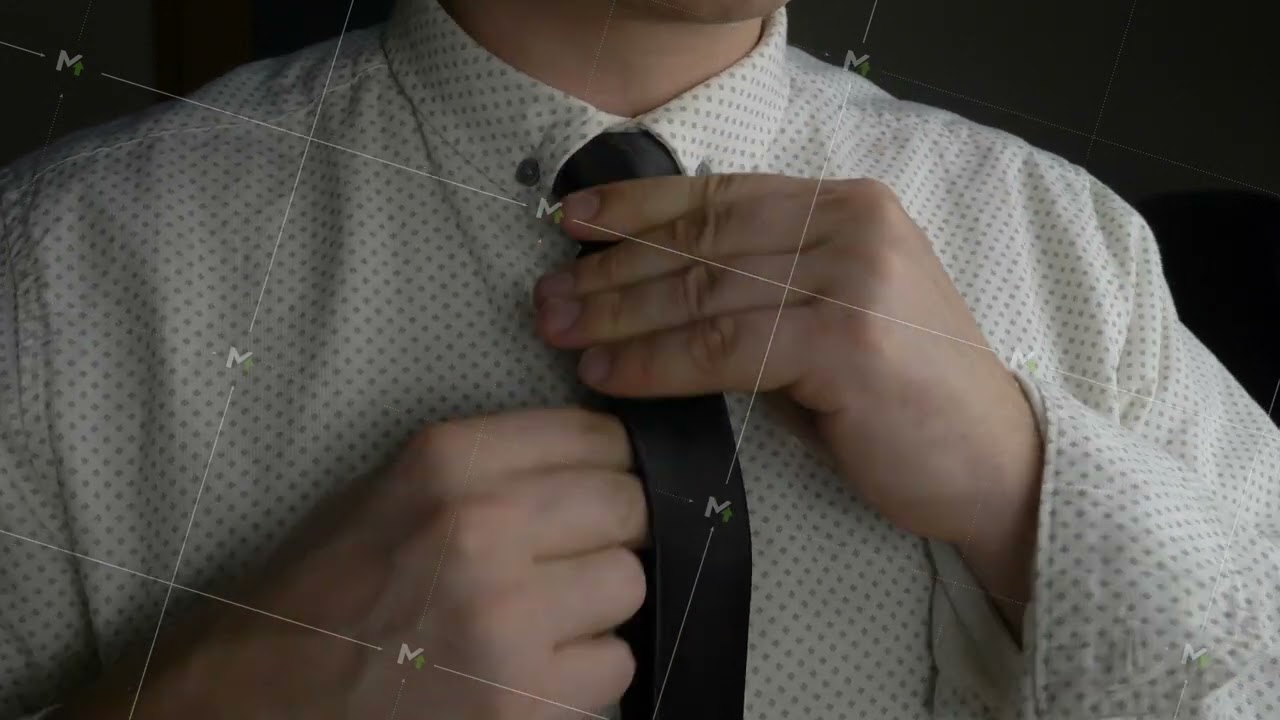 Man adjusts black tie on buttoned shirt