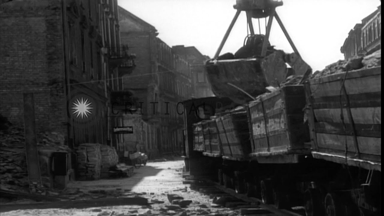 A steam shovel loads rubble into small railroad cars and men load damaged bricks ...HD Stock Footage