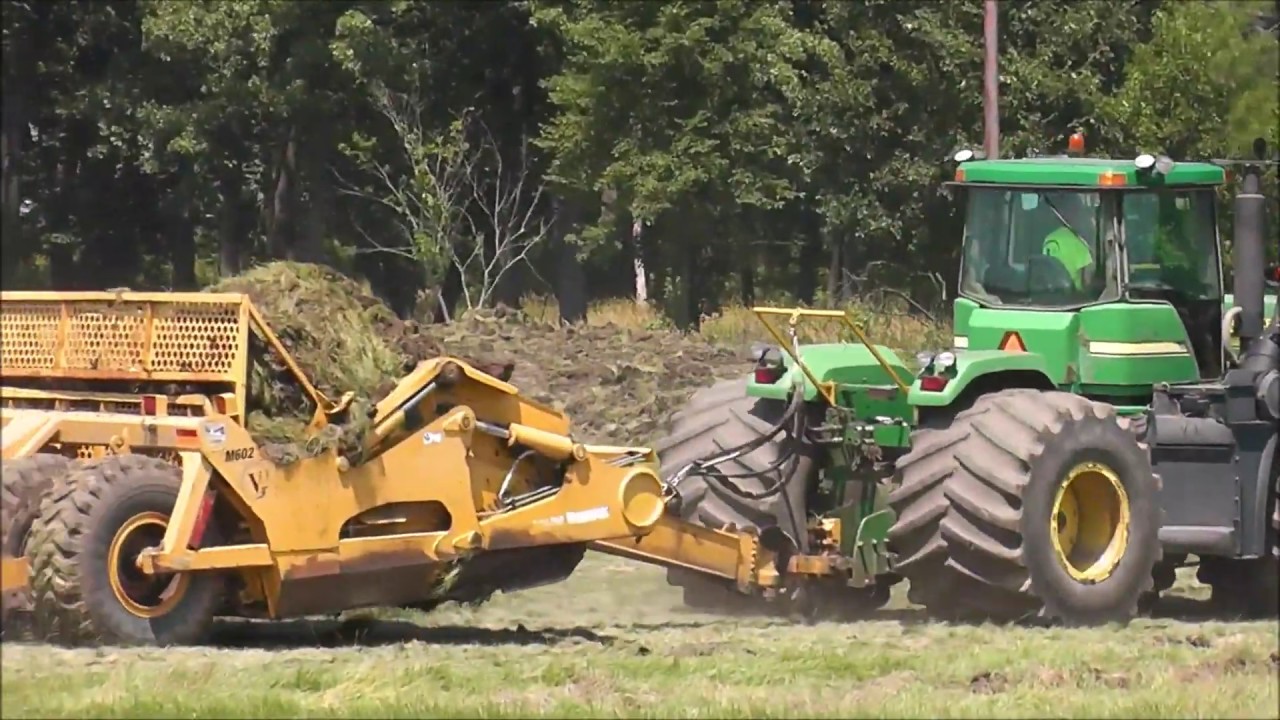 John Deere earth scraper moving grass and dirt