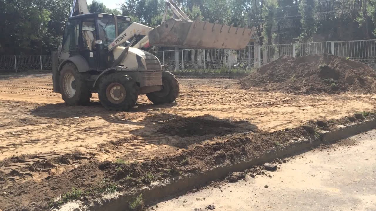 Экскаватор  погрузчик TEREX 860 выравнивает грунт на спортивной площадке в Калуге