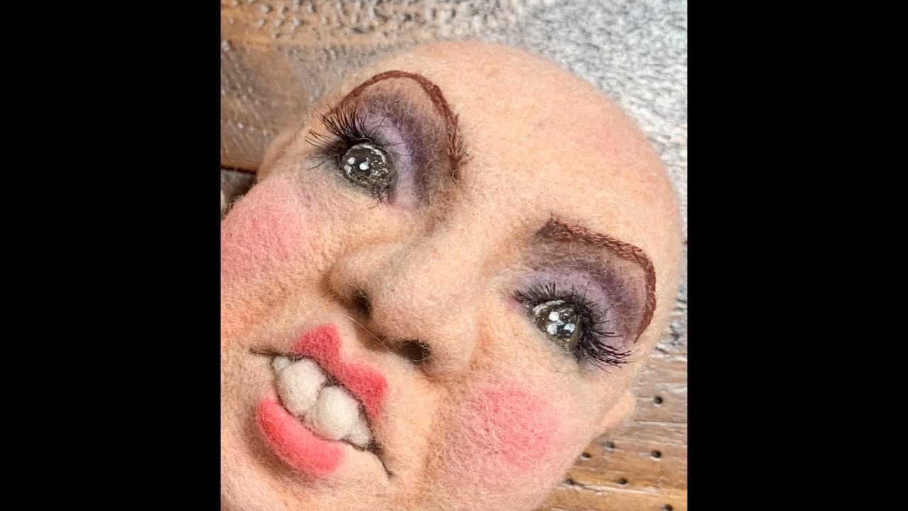 Adding color to a needle felted dolls face using chalk.
