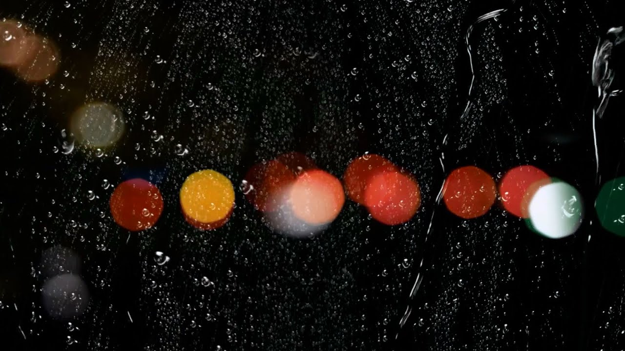Rain Drops on Window Glass,Bokeh Lights Traffic Lights in Background