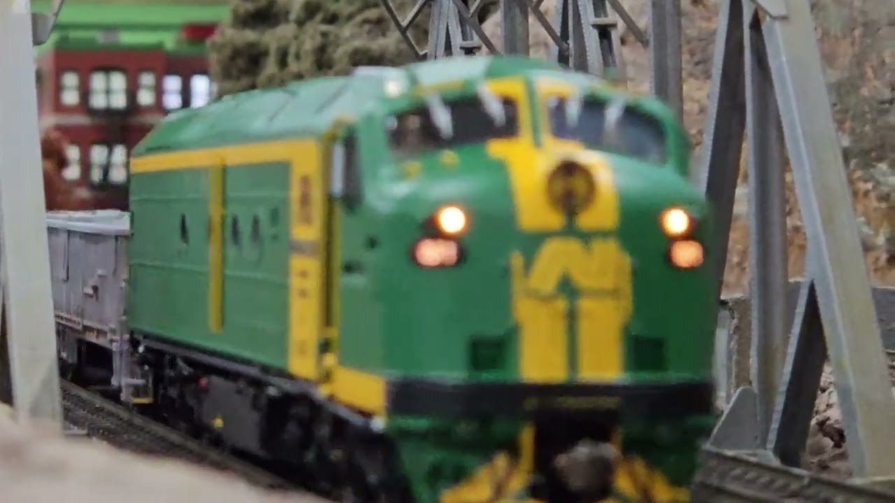 HO Trains AUS and US around the layout over the bridge and into town.