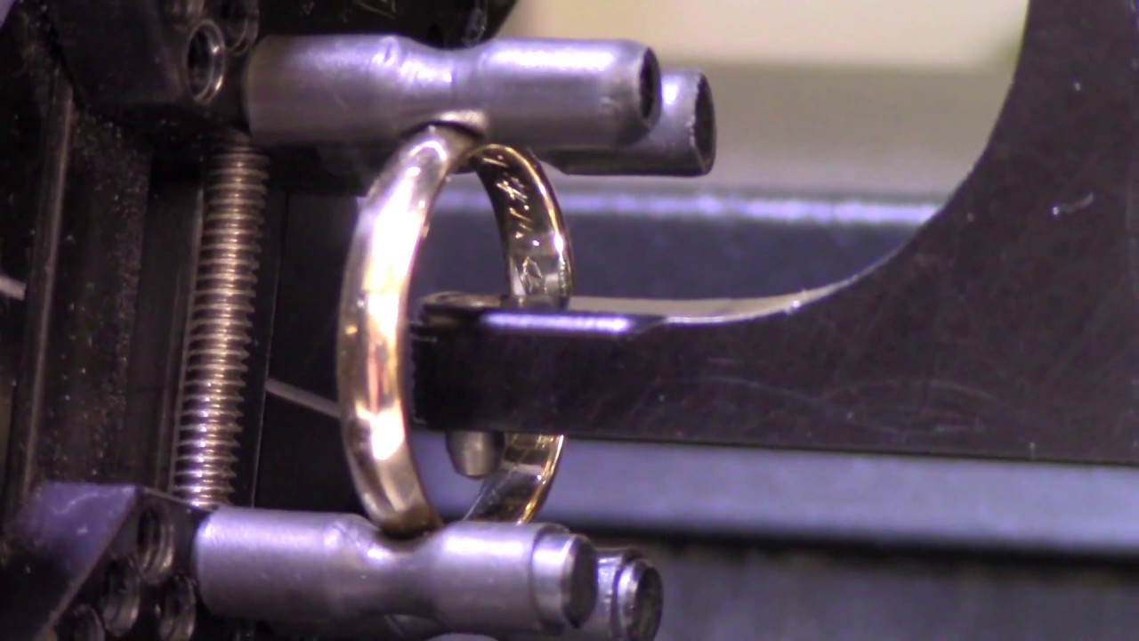 Men's gold wedding ring being engraved.