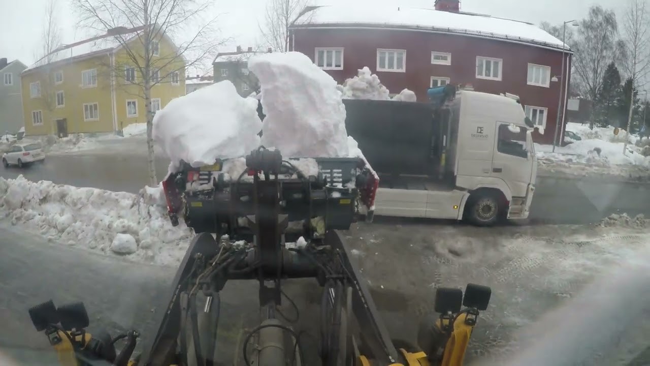 Loading trucks with snow on busy street
