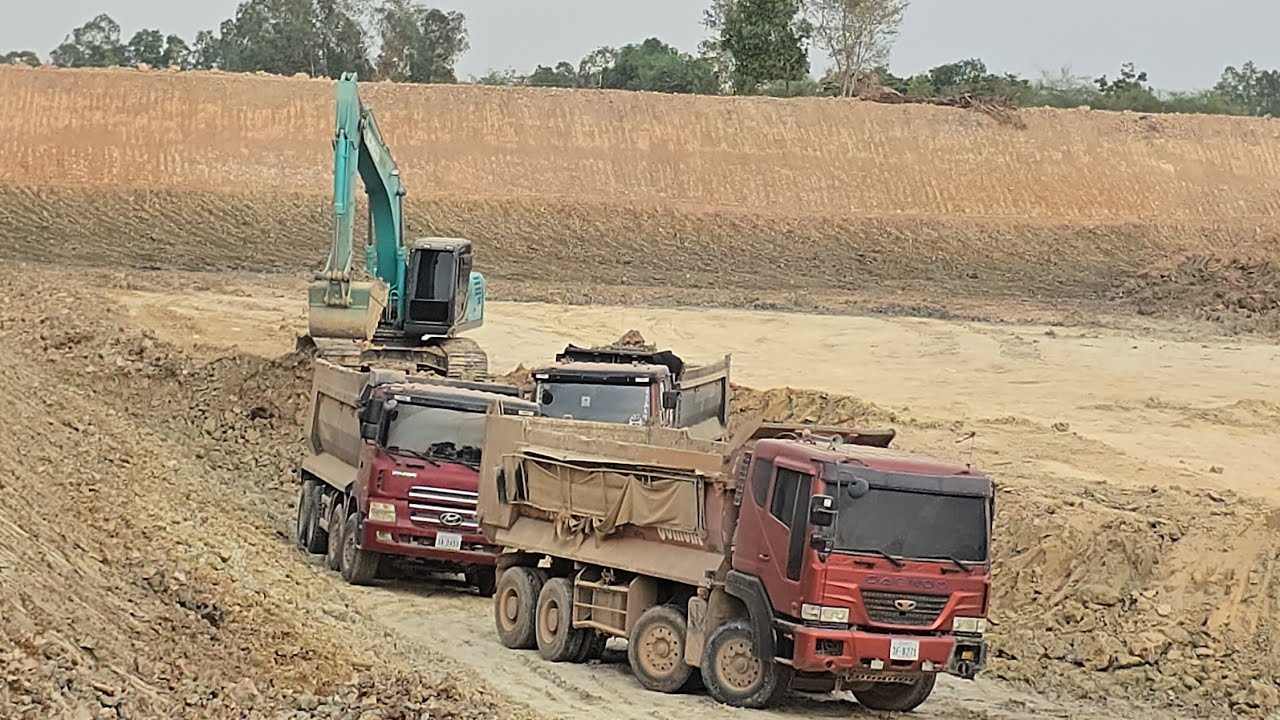 A Kobelco SK 260 LC excavator is loading soil into a 12-wheel Hyundai truck from Korea.