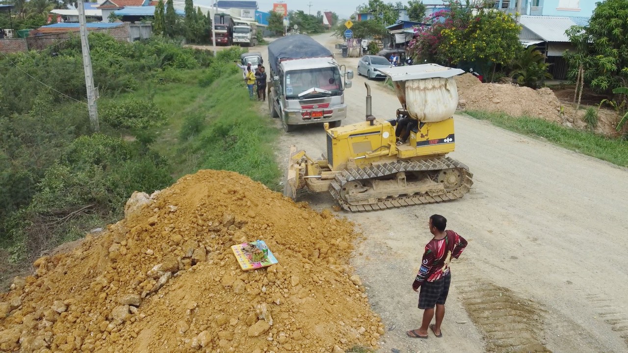 Skilled Land Filling Operation Begins Professional dozer operator and dump truck drivers moving soil