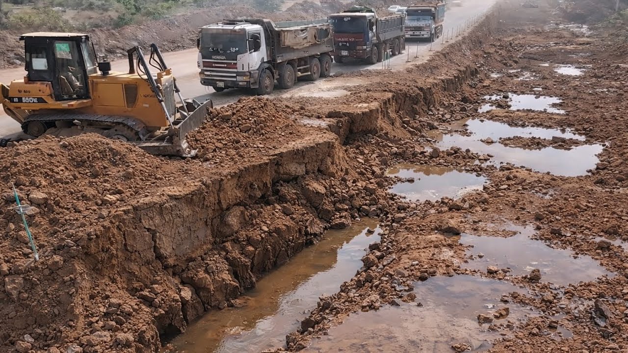 Huge powerful Dozer Pushing Red Soil Repairing Big Road With 25T Dump Trucks