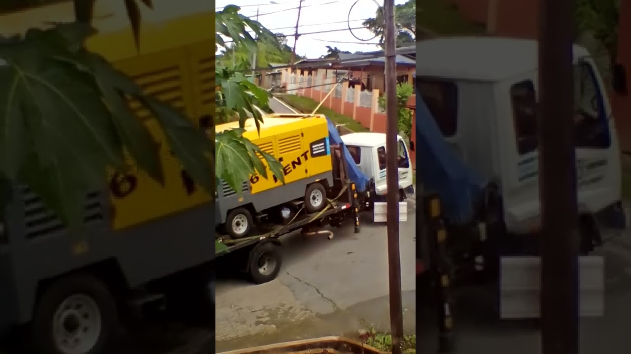 Trinidad Isuzu flatbed crane truck transporting a generator