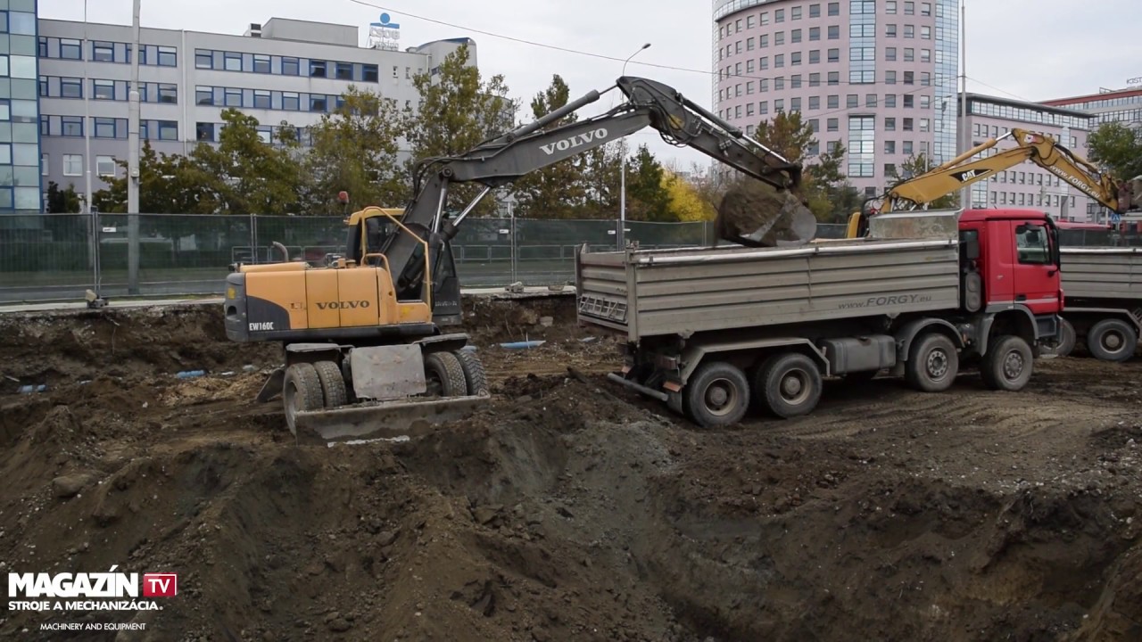 Wheel excavator VOLVO EW160C digging and loading dirt to MB Actros 4144 dump truck