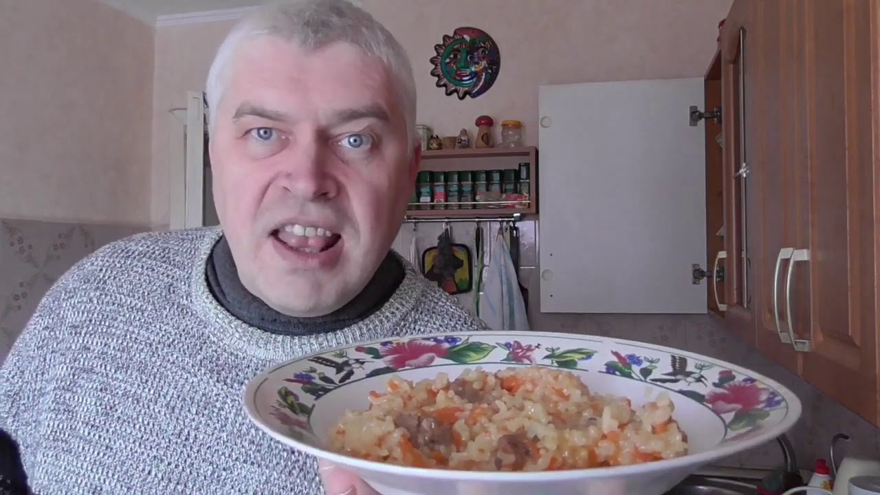 Человек кушает плов на кухне