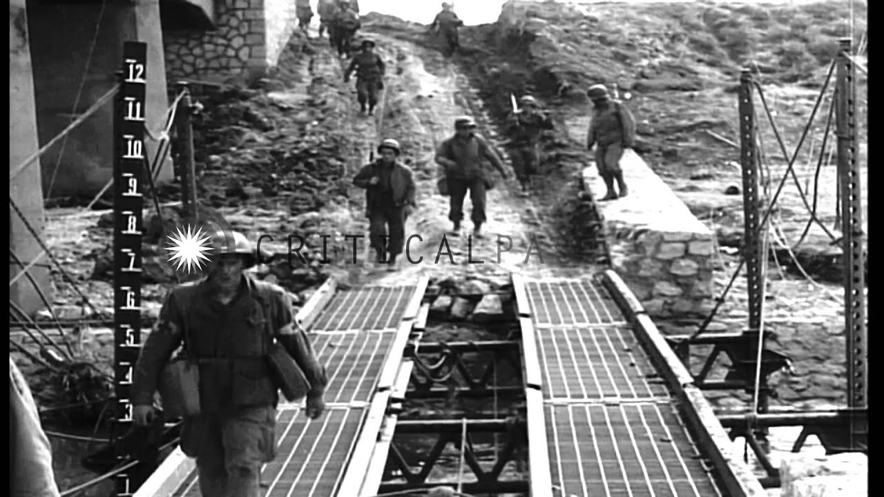 Officers talk near a burning US tank and battle worn US troops walk on a road in ...HD Stock Footage