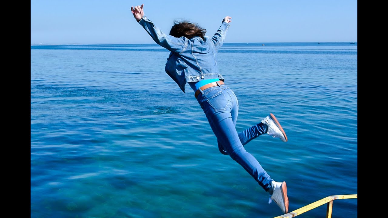 cheerful girl in wet denim jacket and wet jeans tenderly poses on the sea for wetlook video