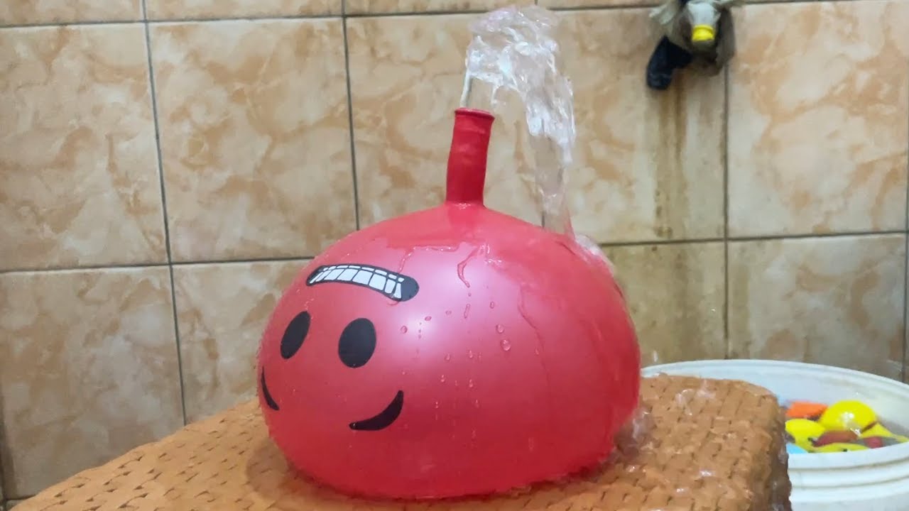 BLOWING UP WATER BALLOONS AND MAKING A DRAMA OF BALLOONS EXPLODING, UNTIL WATER SPRINGS