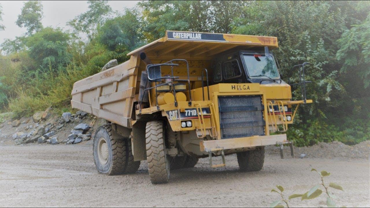 A bunch of Caterpillar 771D trucks hauling granite rock to the crusher
