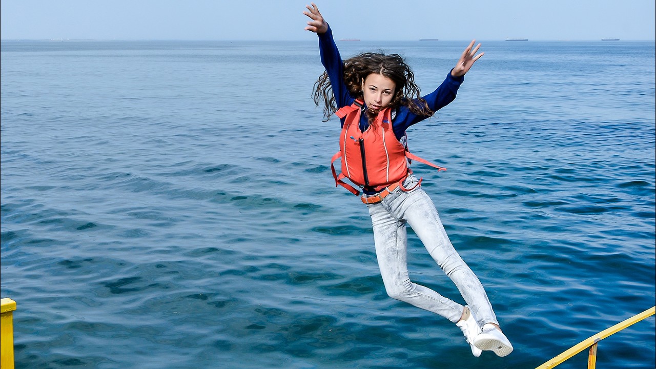 WETLOOK! A CUTE GIRL IN CLOTHES JUMPS FROM A BREAKWATER INTO THE SEA AND THEN POSES IN WET CLOTHES!