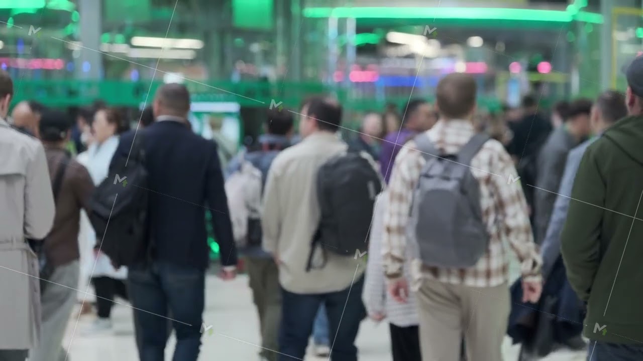 Crowd of commuters with backpacks walking through busy modern transit hub, blurred motion