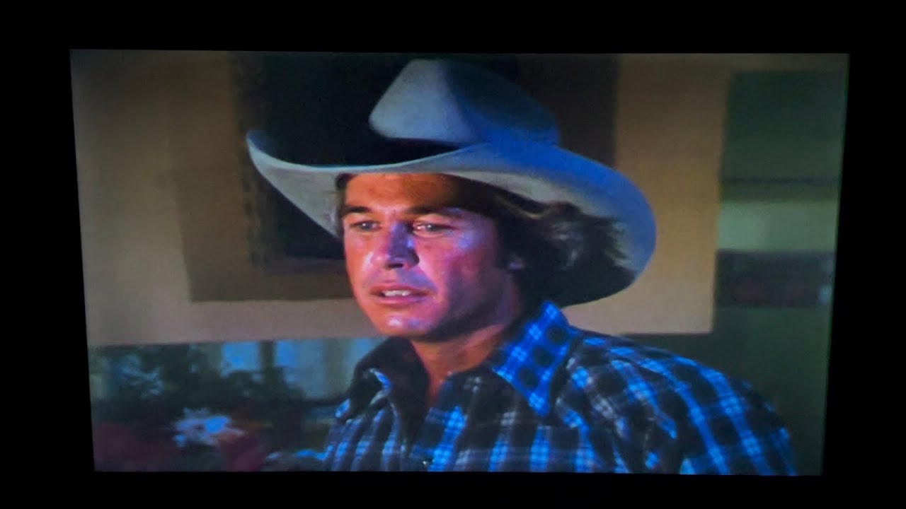 Dallas: Ray catches J.R. in bed with Garnet McGee.