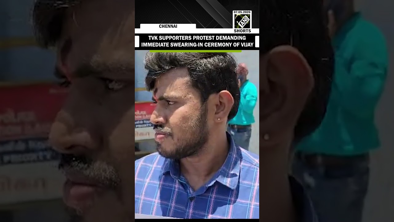 Two TVK supporters hold posters demanding an immediate swearing-in ceremony of TVK chief Vijay as CM