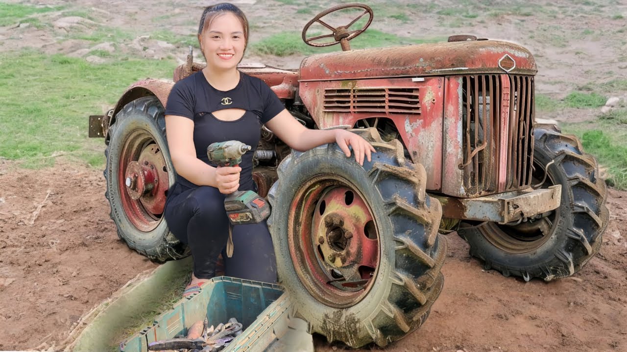 A girl is repairing a broken agricultural tractor found beside a field