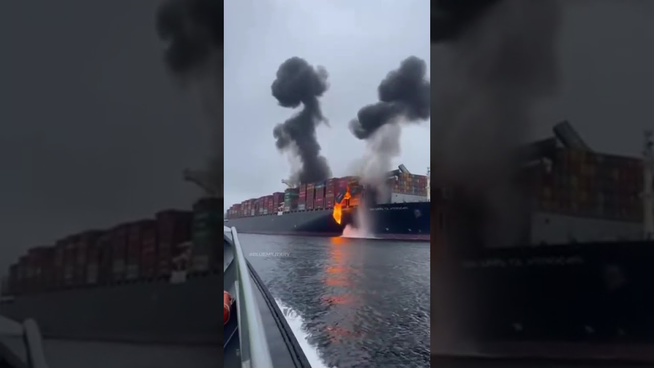 A massive explosion on a cargo ship at sea, with black smoke billowing into the sky.