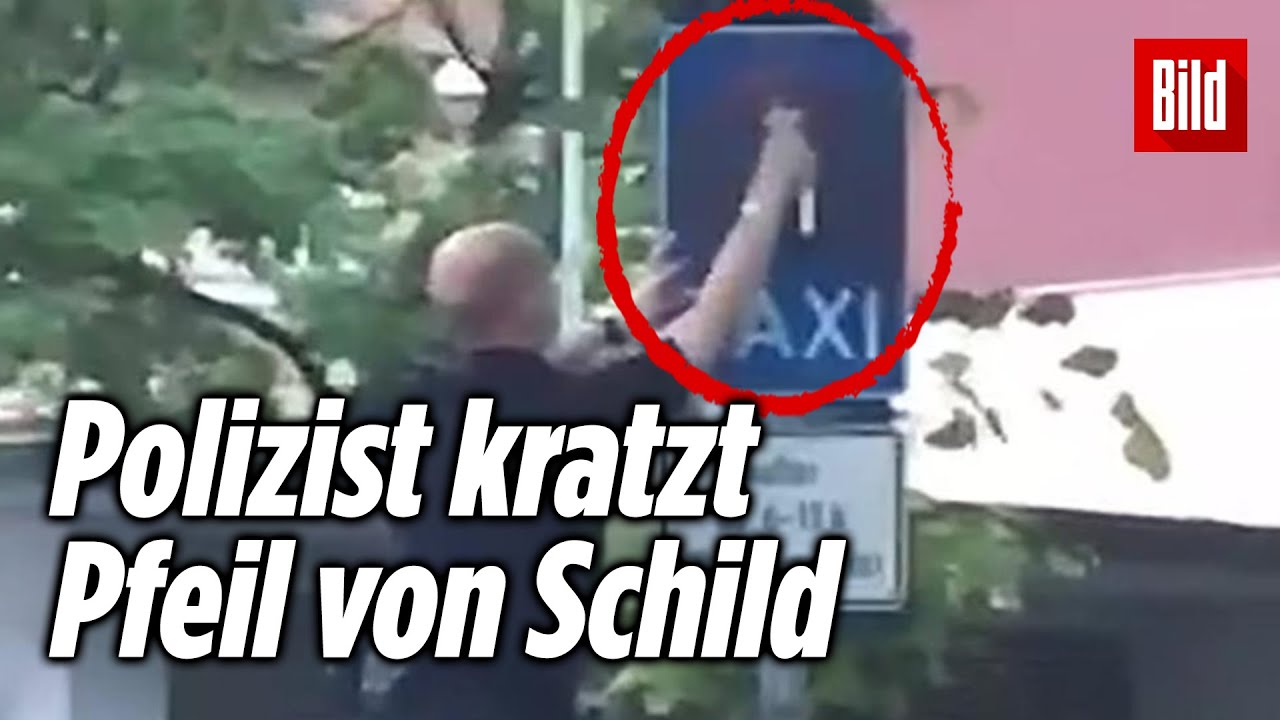 Polizist kratzt Pfeil von Verkehrsschild, um Knöllchen zu schreiben
