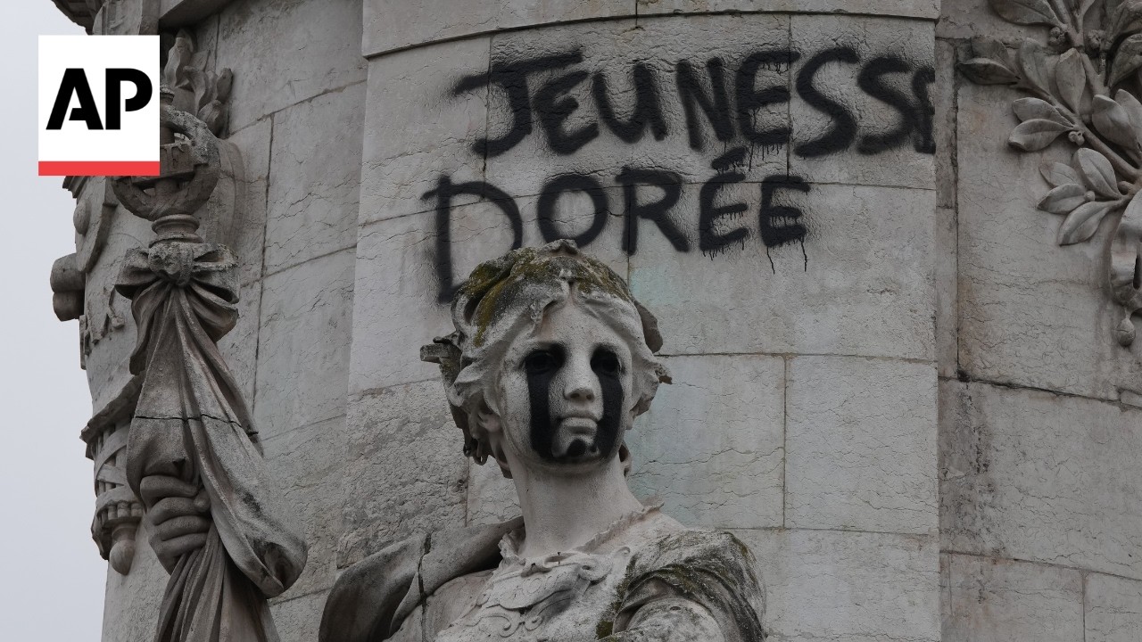 Workers remove graffiti from a monument and clean up after Paris riots