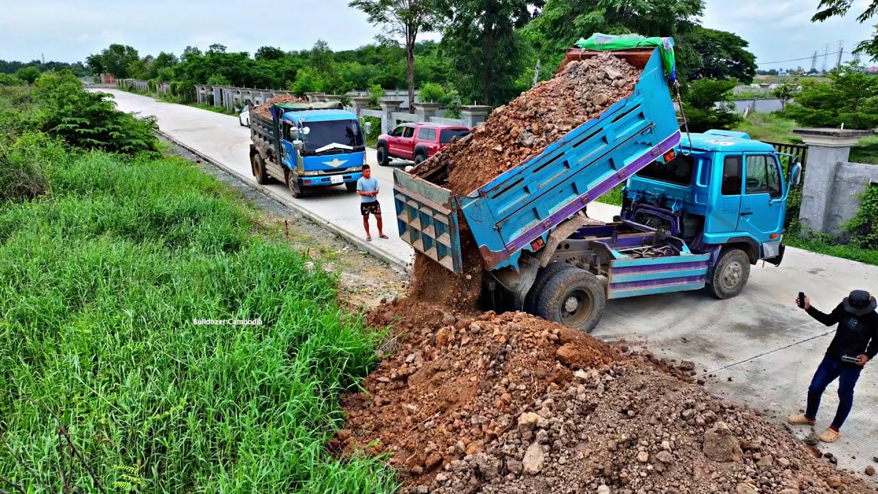 5T Trucks Loading Rock And Small Dozer Pushing Filling a big sink hole