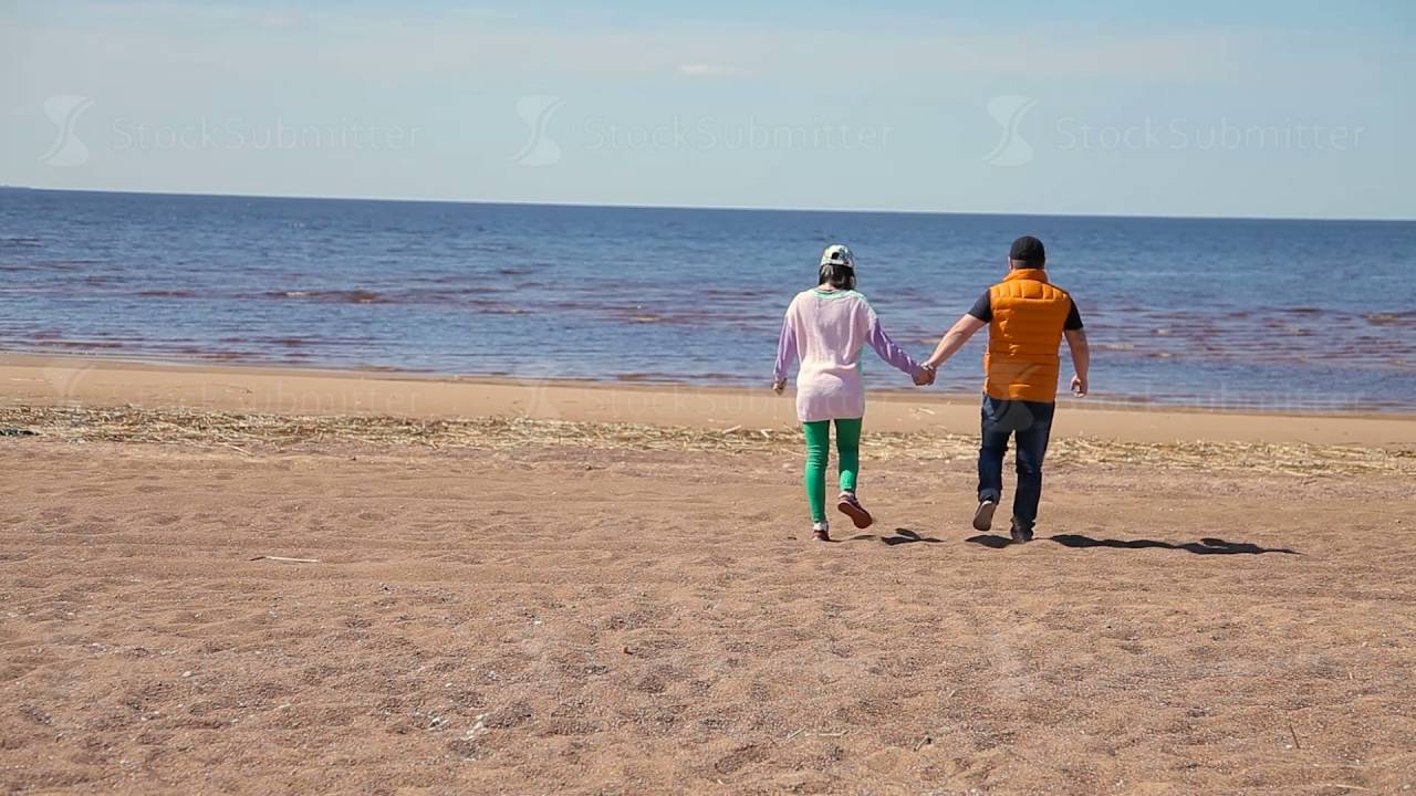 Happy Romantic Young Couple Walking Down the Beach