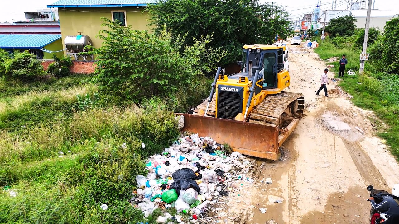 Bulldozer clears garbage, waste and clean land then fill with dirt and soil with dump trucks