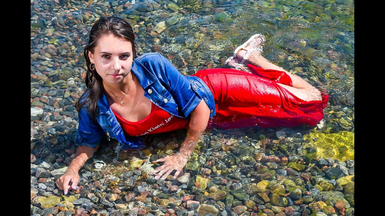 girl in a red dress gets wet in the sea