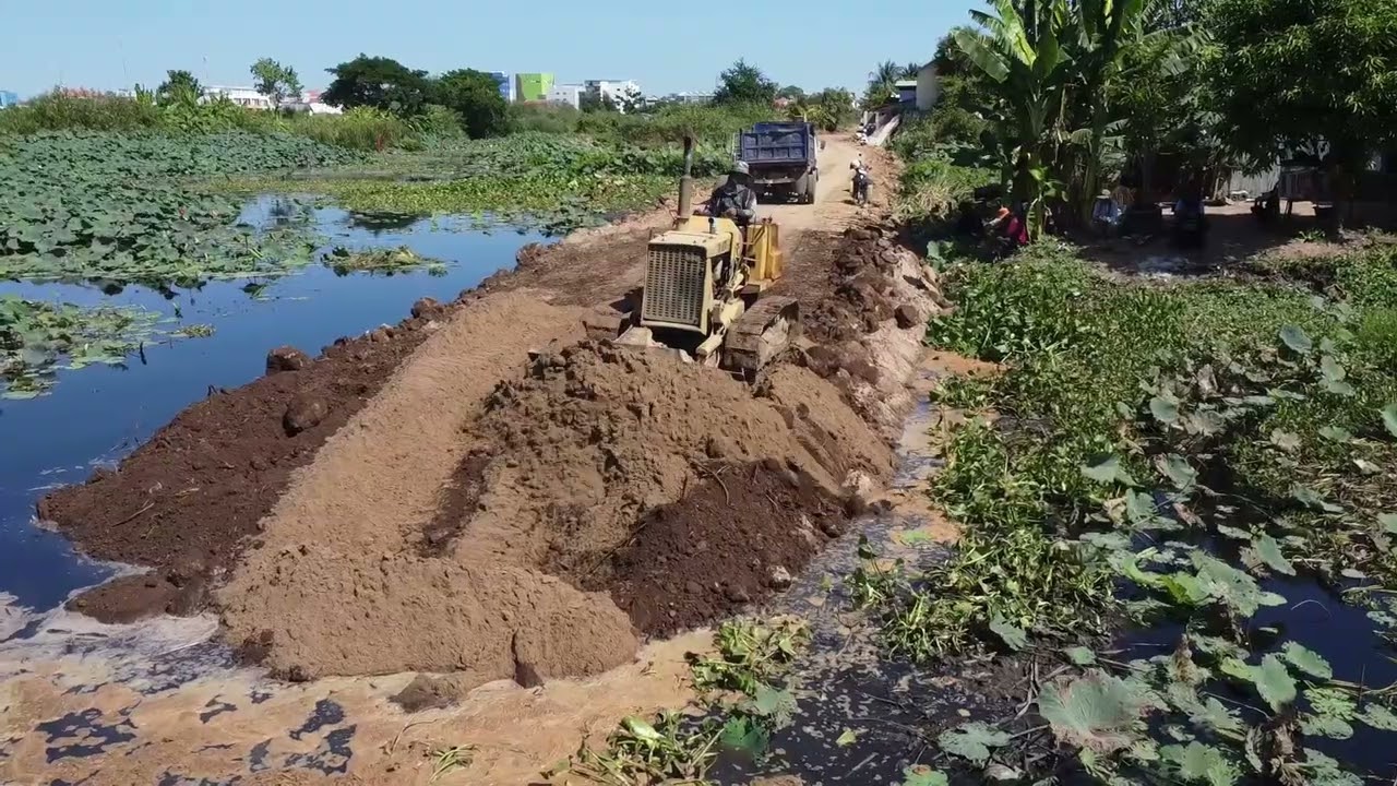 Powerful Bulldozer Pushing Dirt into Water for Road Project
