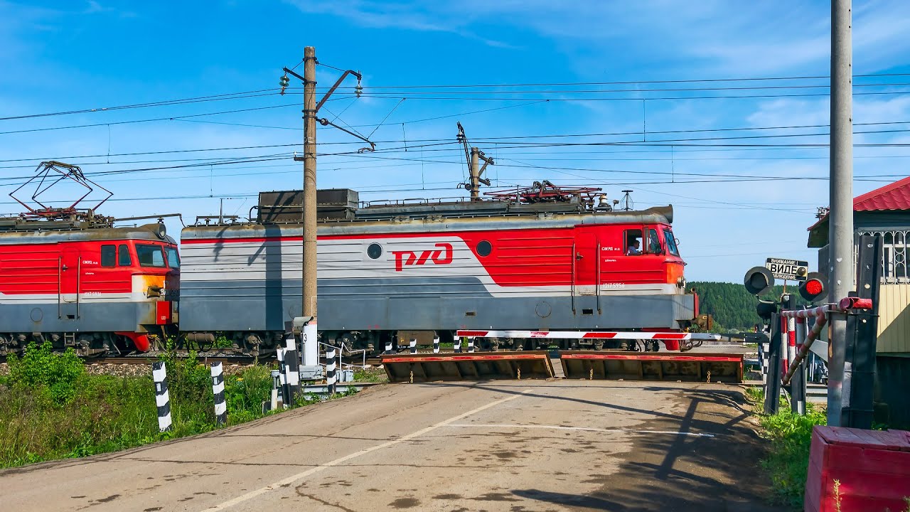 ЖЕЛЕЗНАЯ ДОРОГА. Старый и новый электровозы с грузовыми поездами на железнодорожном переезде