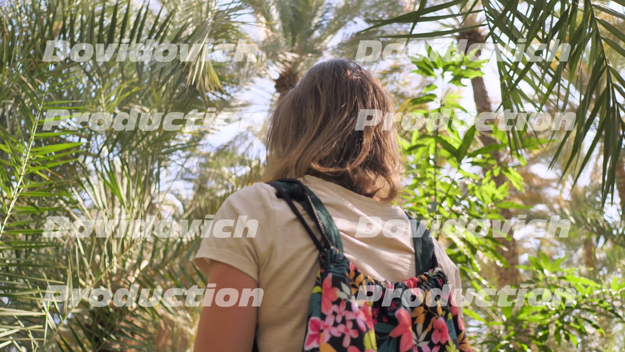 A girl walks through the palm jungle.