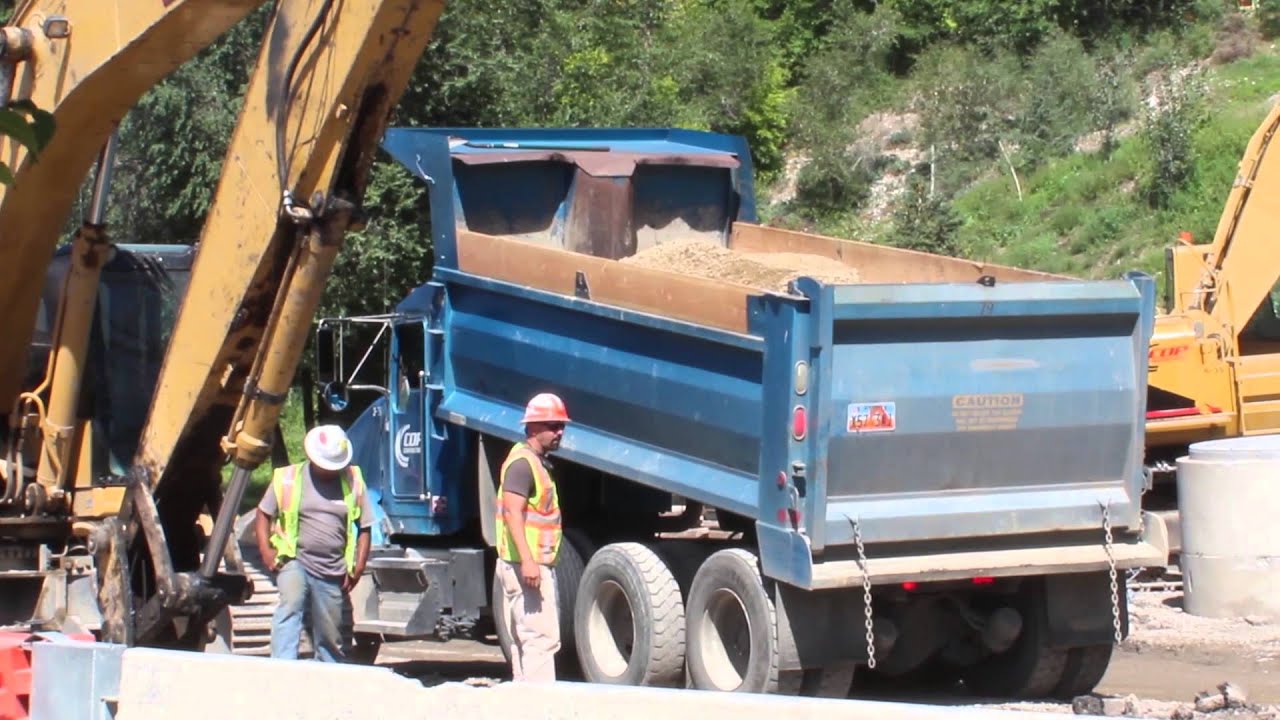 Blue Kenworth Dump Truck dumping dirt on a road construction site