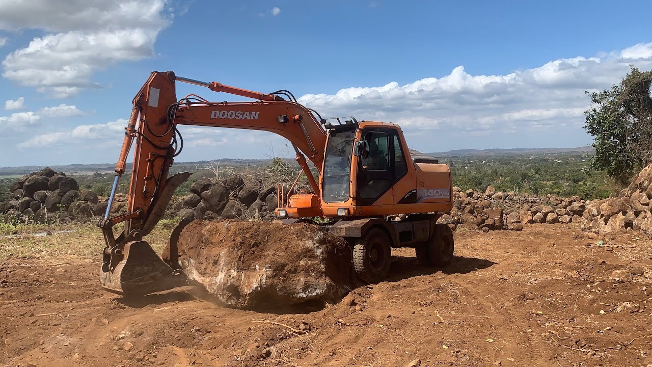 2 xe múc Doosan lớn mang cục đá to lên và di chuyển ra bờ biên