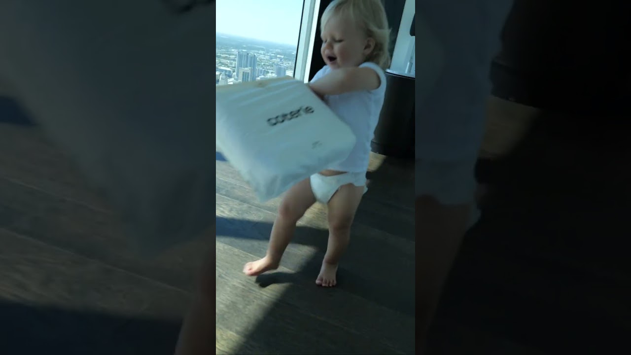 Cute Baby Naomi is playing with packs of Coterie Diapers