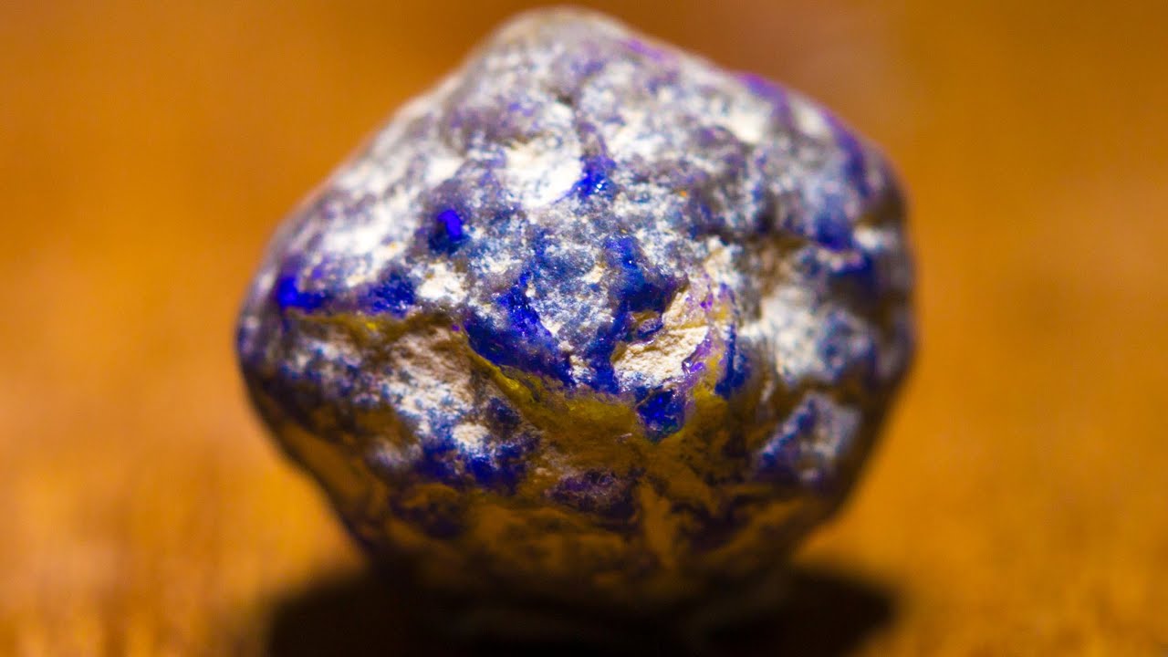 This blue glowing rock is a rough black opal waiting to be cut