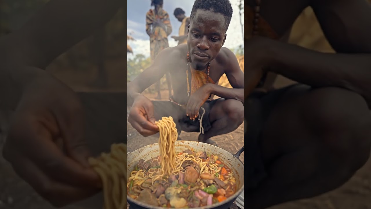 Hadzabe eating grilled meat strips over firewood flames.#Hadzabe #PrimitiveCooking #ForestCooking