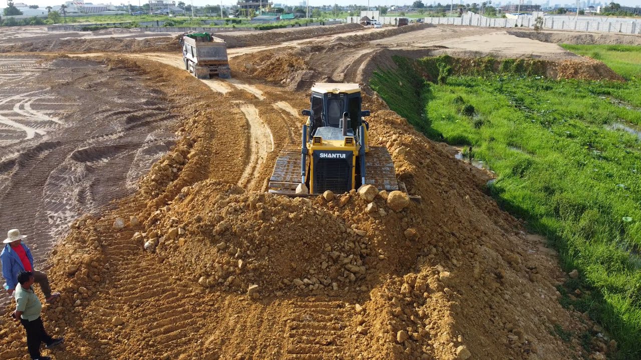Good job! Dozer SHANTUI is clearing the land, making a border with a heavy trucks
