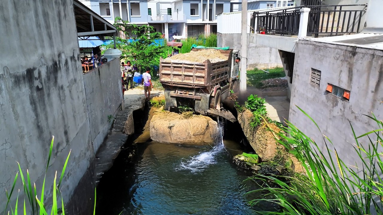 Dump Truck Dumping dirt to Delete Flooded from bulldozer push