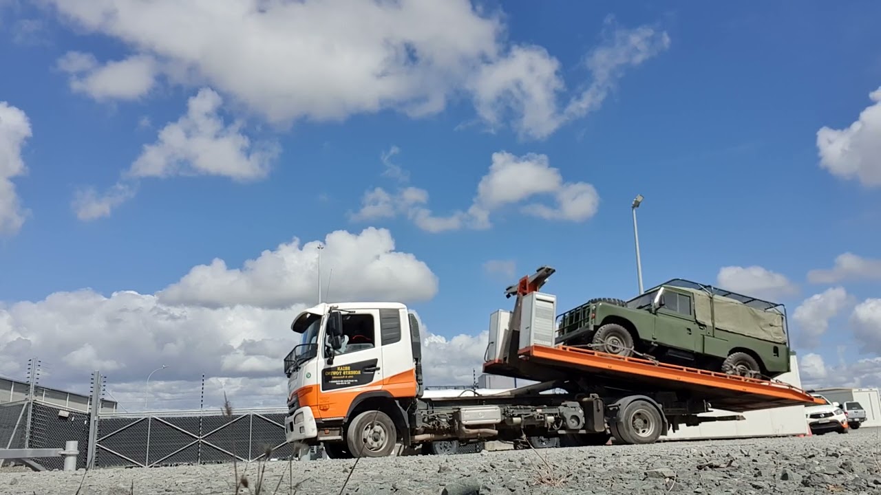 Loading an old Land Rover with a Hook Lift Flat Deck tow truck